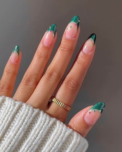 Hand with green French manicure and gold ring, resting on a white sweater.