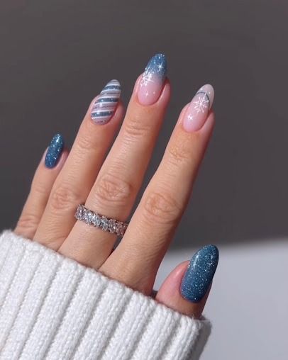 Hand with glittery blue and pink ombré manicure, wearing a silver ring and white sweater sleeve