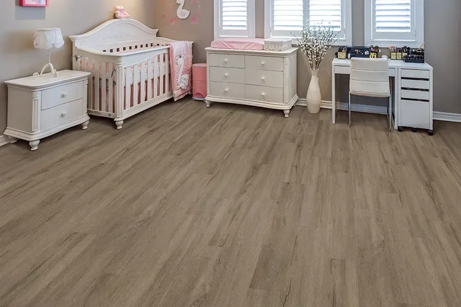 There is a crib, dresser, desk and nightstand in the room.