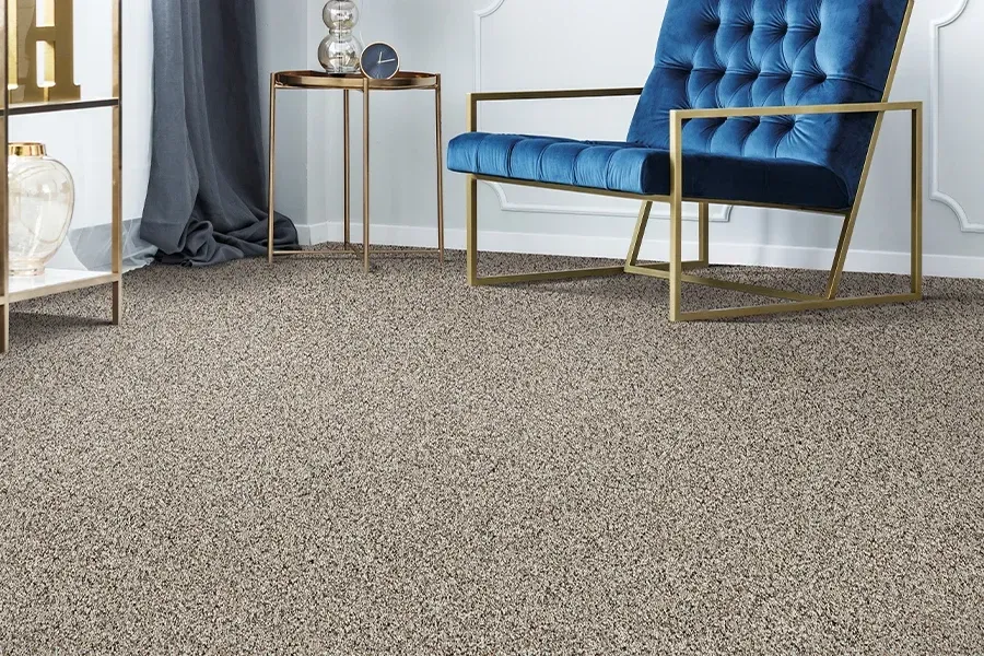 A living room with a blue chair and a carpeted floor.