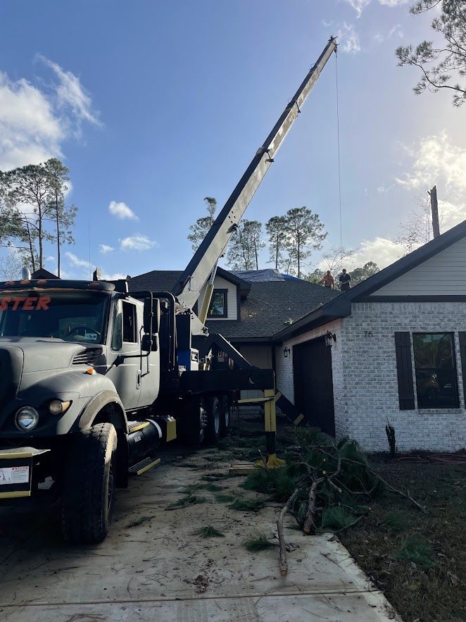 A truck with a crane attached to it is parked in front of a house.