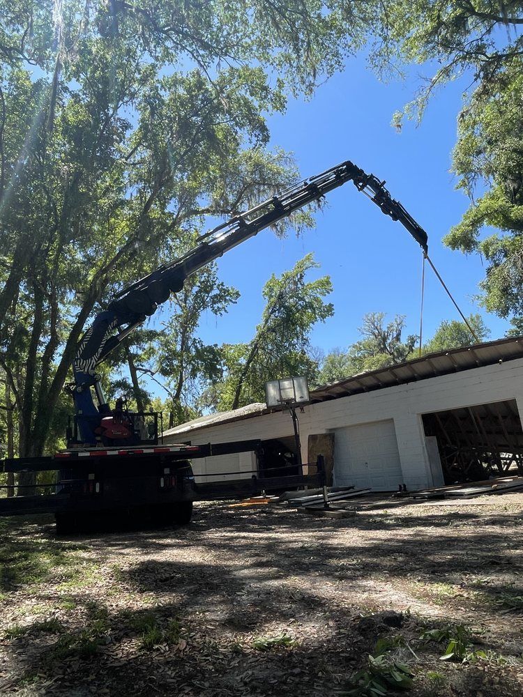 A crane is lifting a large piece of wood in front of a building.