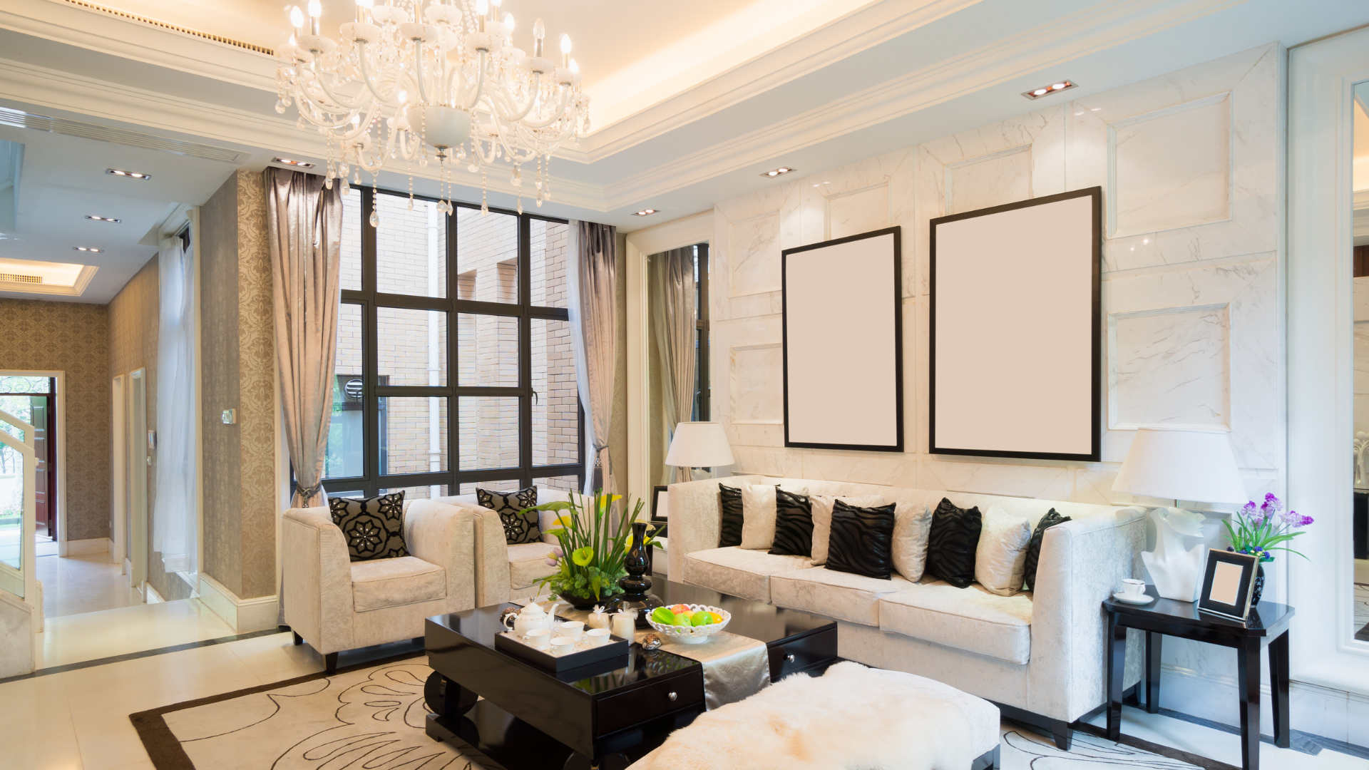 Elegant white living room with crystal chandelier, black-accented seating, and large framed wall art