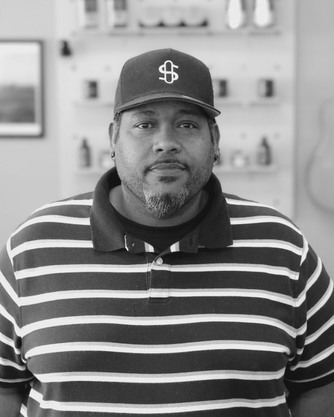 A man wearing a green hat and a black shirt is standing in a room.