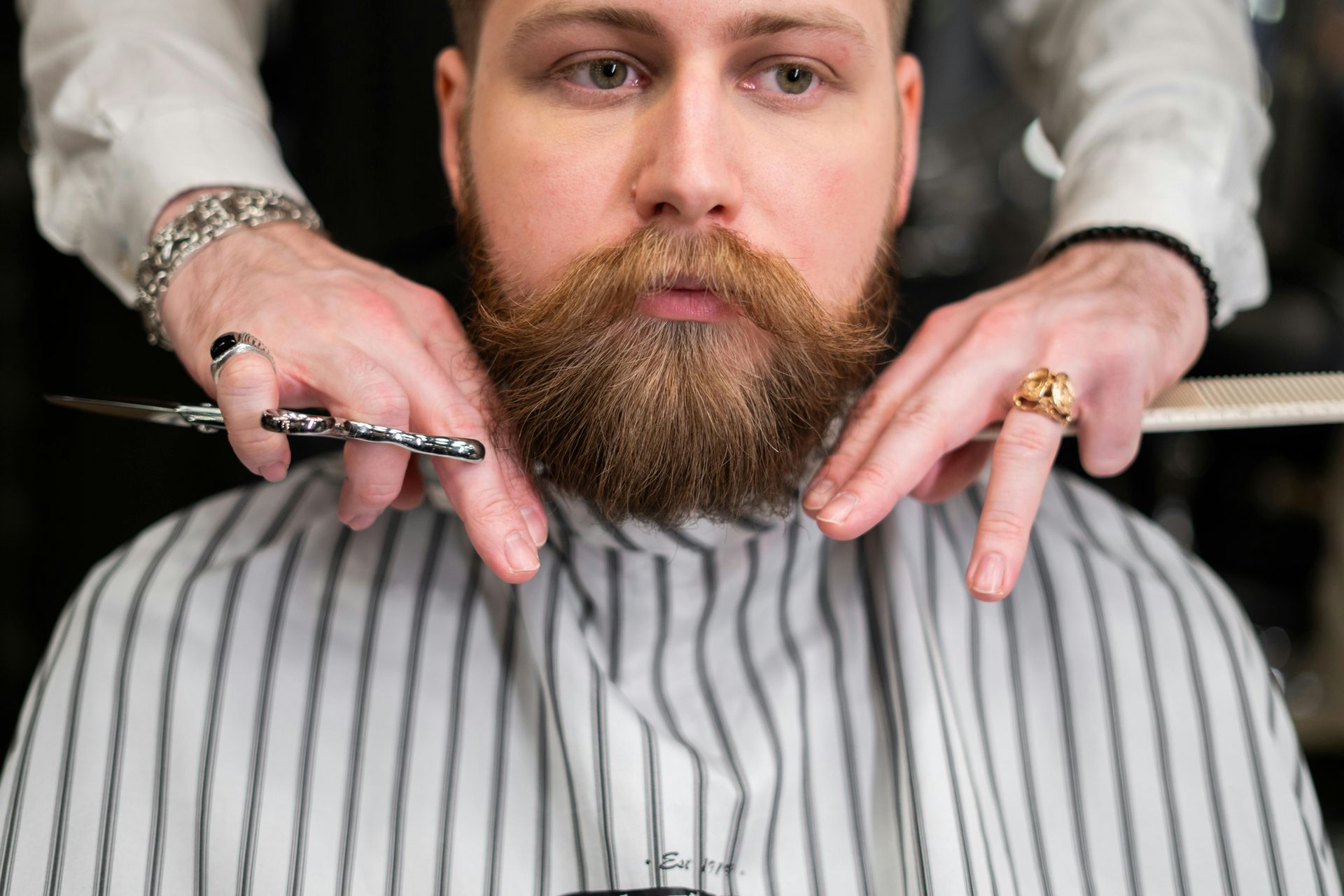 A man is getting his beard cut by a barber.