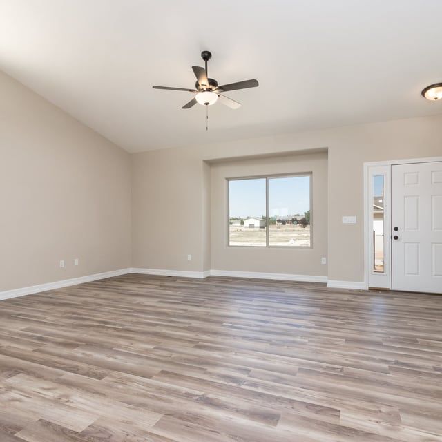 An empty living room with hardwood floors and a ceiling fan