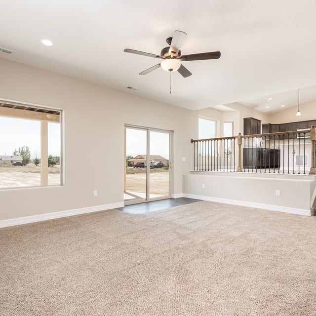 A living room with a ceiling fan and sliding glass doors