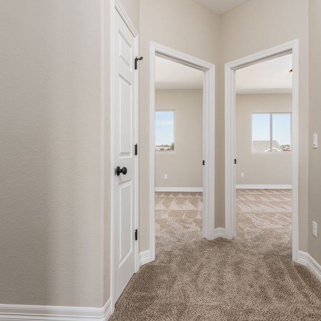 A hallway with a carpeted floor and two doors leading to a bedroom.