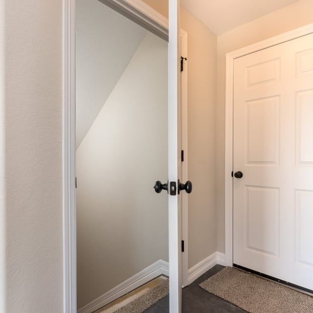 A hallway with a staircase and a door that is open