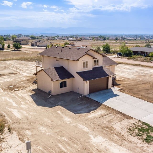 An aerial view of a house in the middle of a dirt field