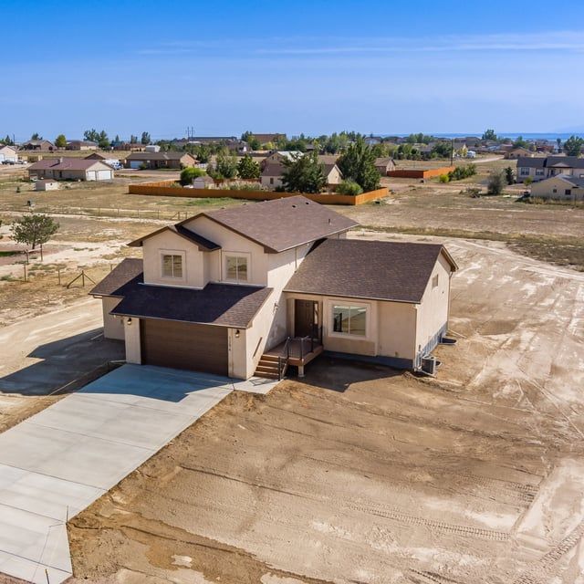 An aerial view of a house in the middle of a dirt field