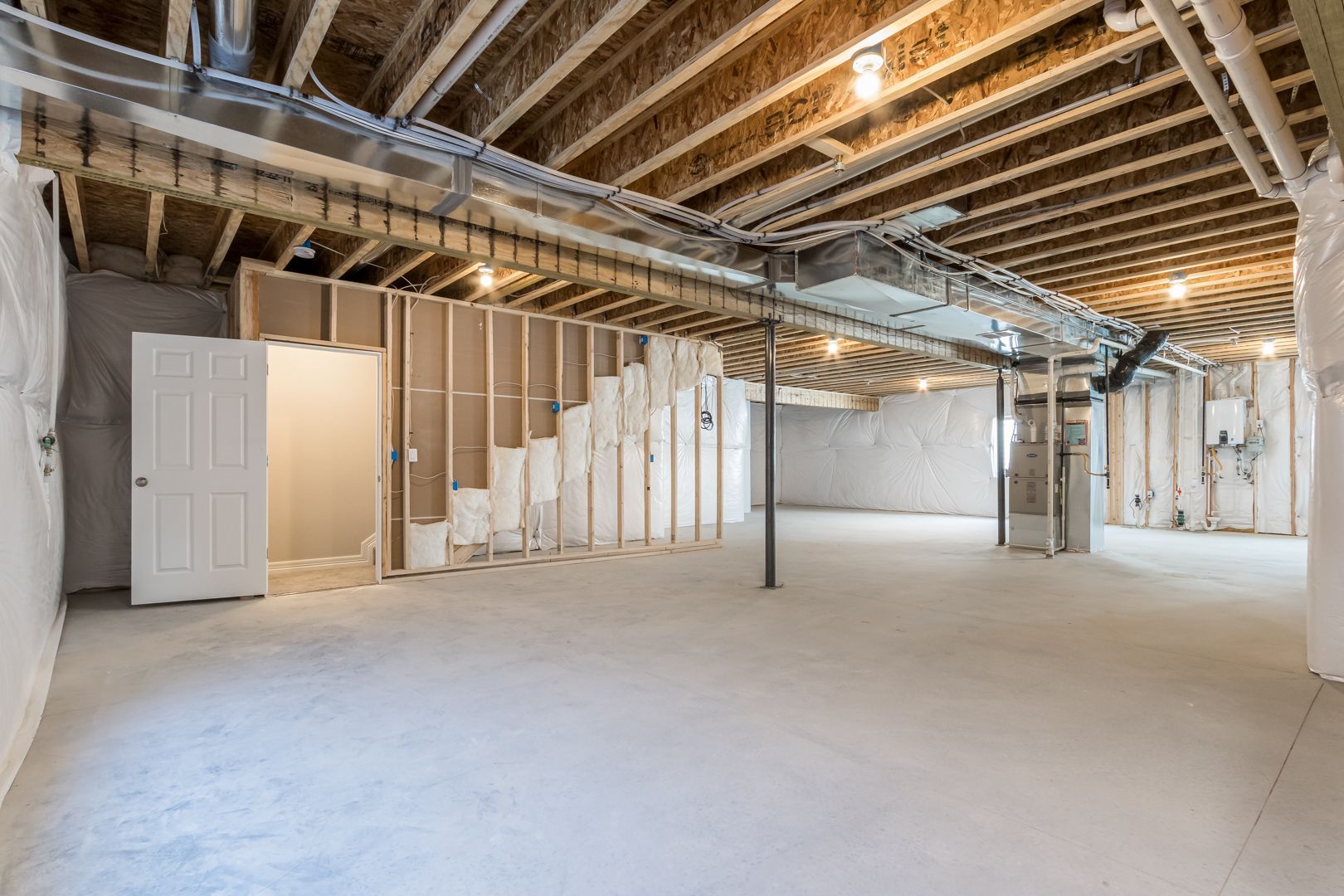 An empty basement with a wooden ceiling and a door.