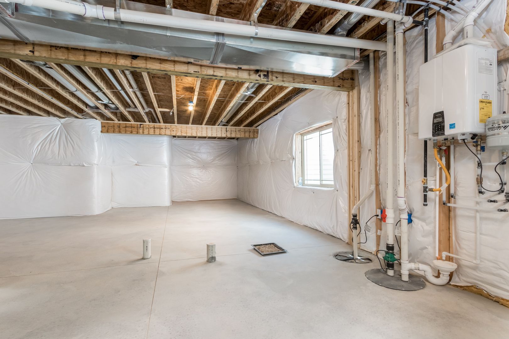 An empty basement with a heater and pipes.