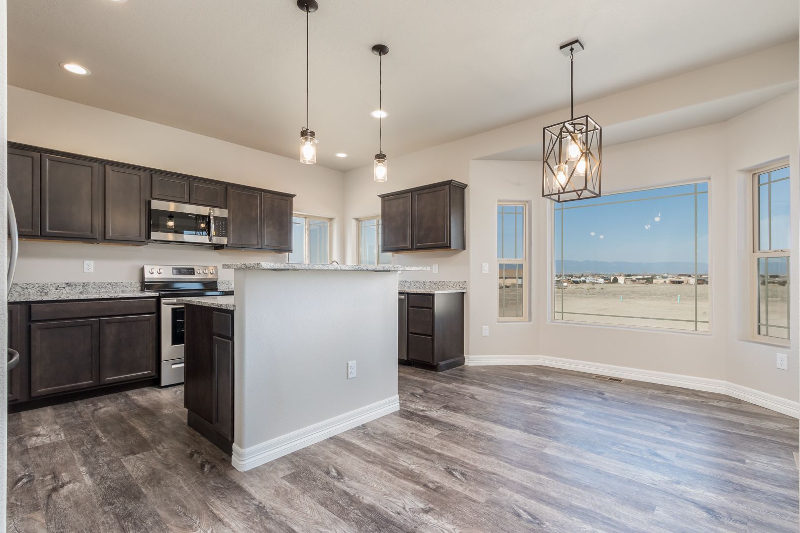 A kitchen and dining room in a new home with hardwood floors and stainless steel appliances.