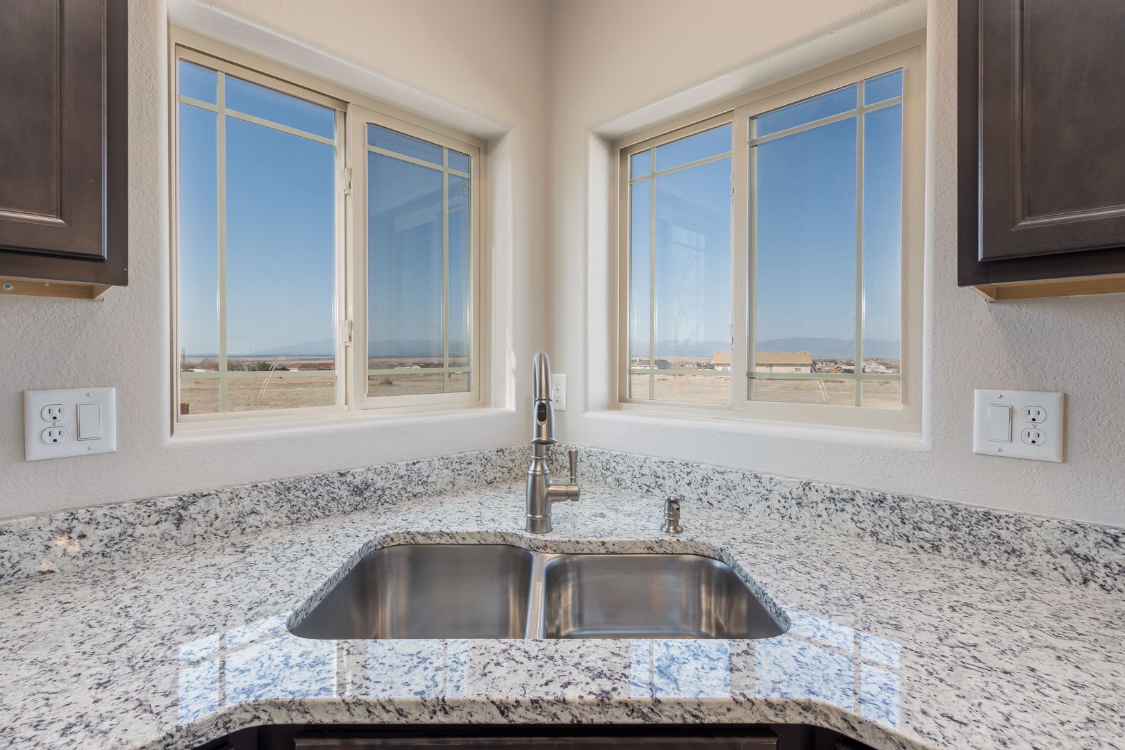 A kitchen with granite counter tops and a stainless steel sink.