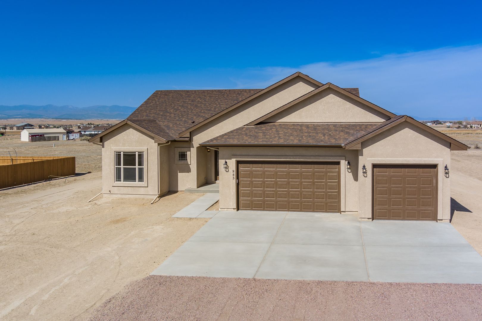 A house with two garage doors is sitting in the middle of a desert.