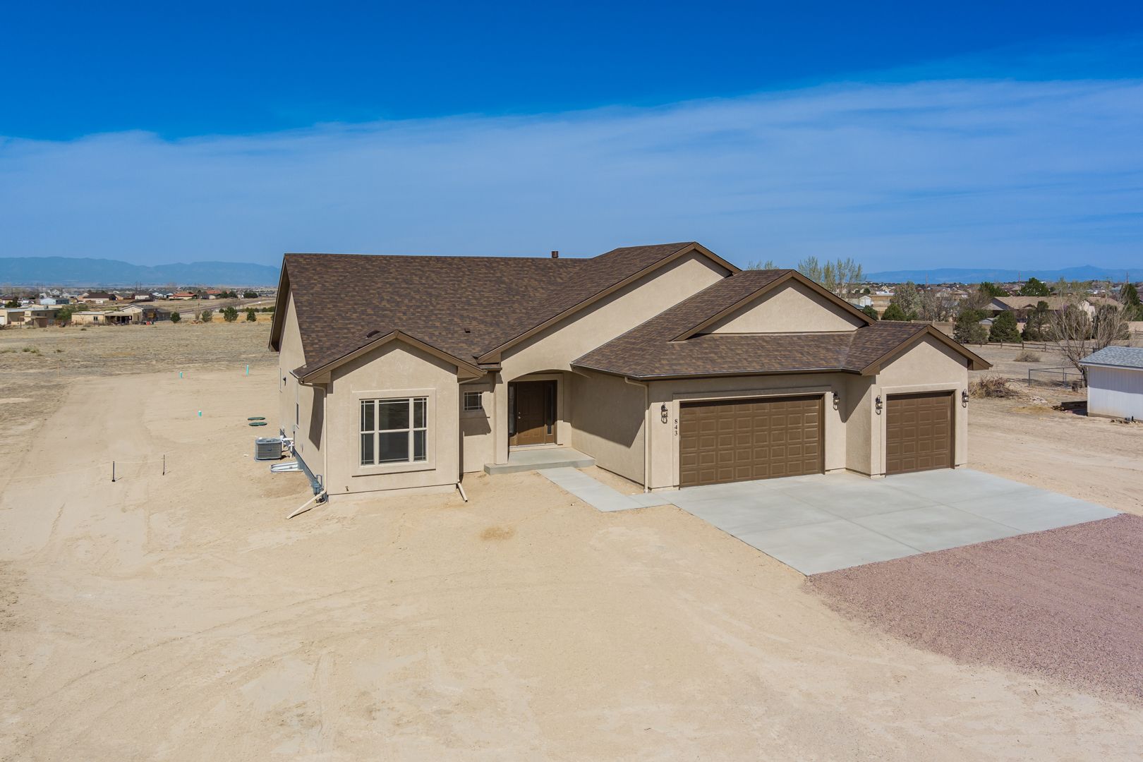 An aerial view of a house with two garages in the desert.