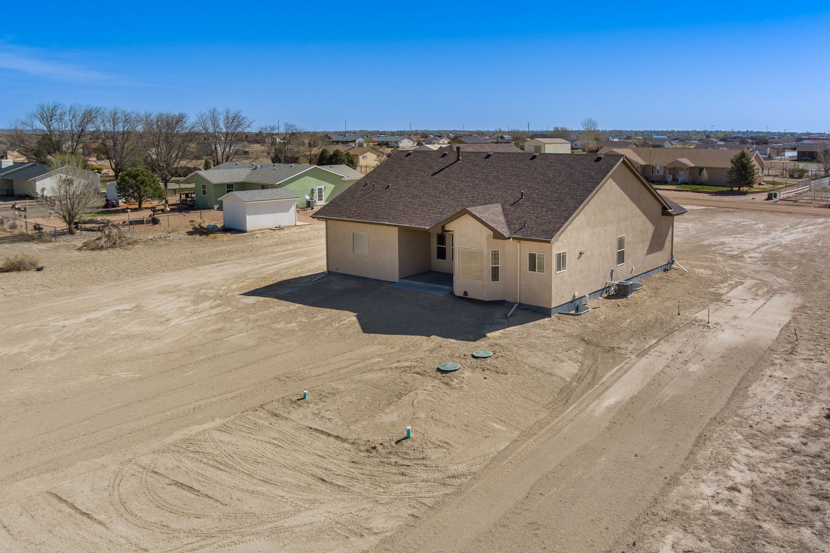 An aerial view of a house in the middle of a dirt field.