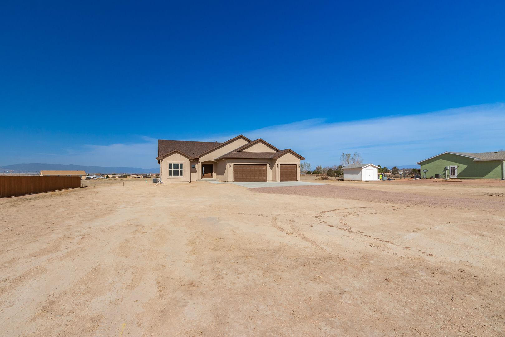 A house is sitting in the middle of a dirt field.