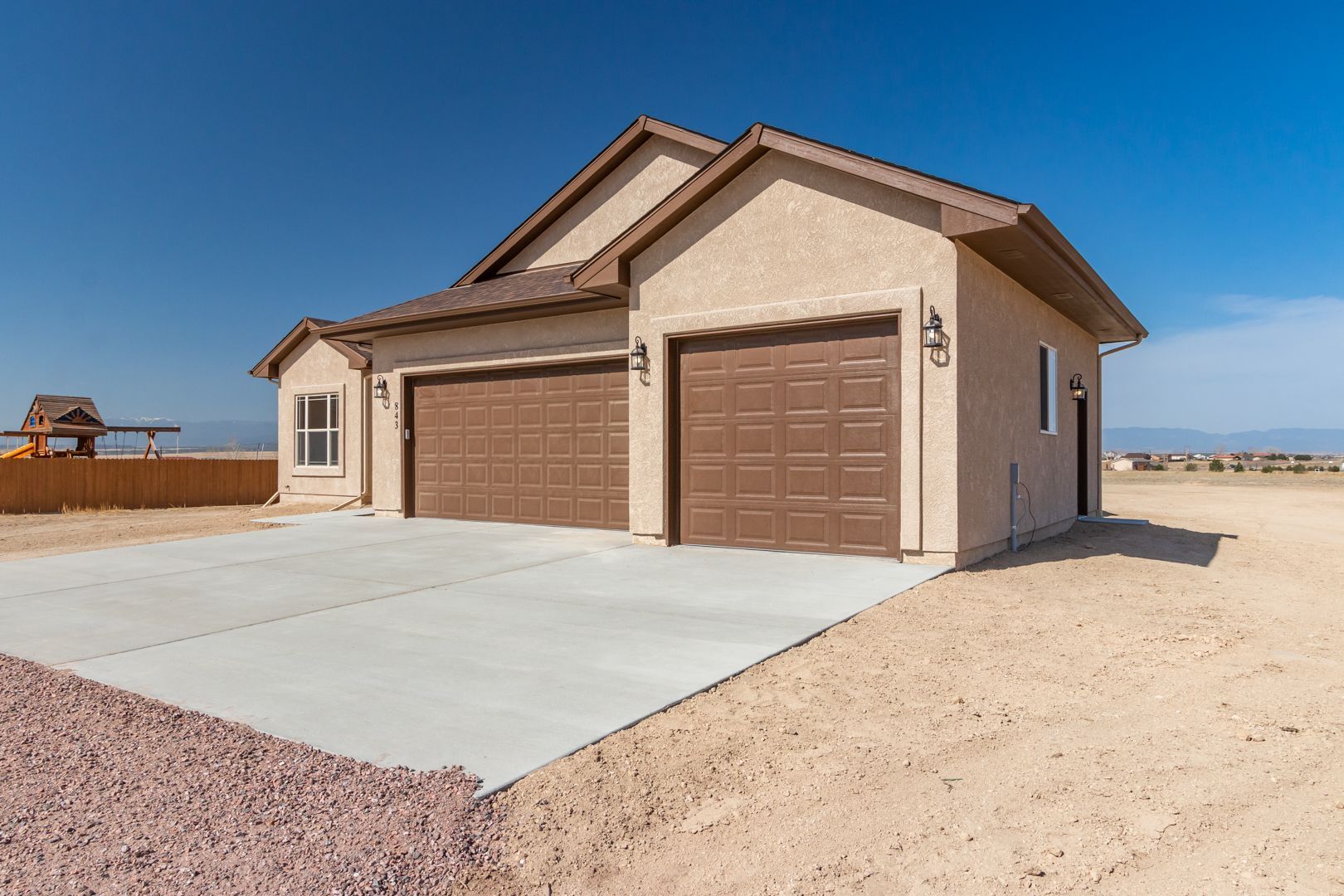 A house with two garage doors and a concrete driveway