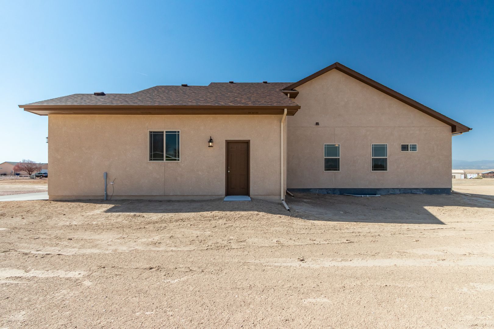 A house is sitting in the middle of a dirt field.