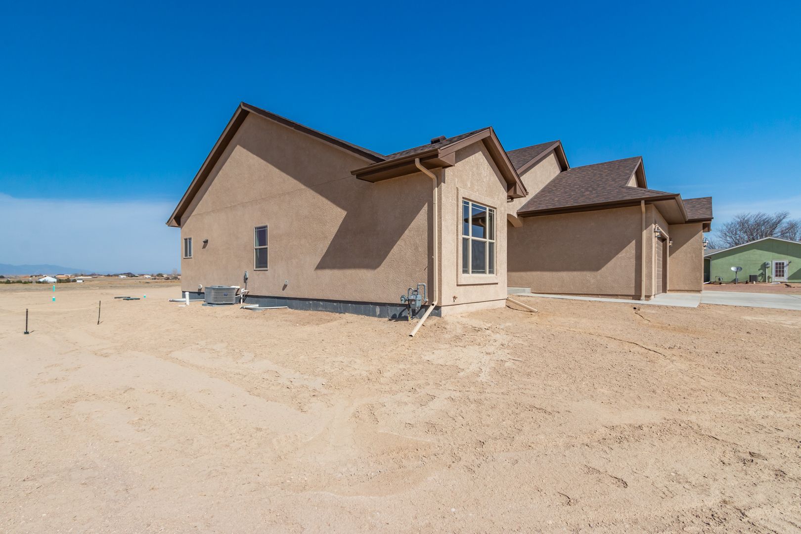 A house is sitting in the middle of a dirt field.