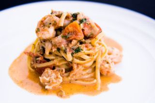 Plated spaghetti with tomato sauce, grated cheese, and herbs on a blue dish