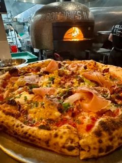 Close-up of a cheese and ham pizza with mushrooms on a wooden table