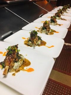 Plated sliced roast meat over mashed potatoes, garnished with herbs on a white plate