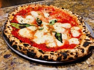 Slice of margherita pizza with basil on a wooden board, close-up view