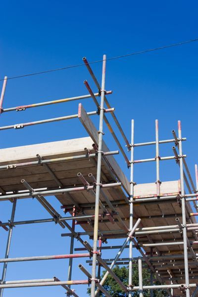 Una fila de andamios contra un cielo azul en un sitio de construcción.