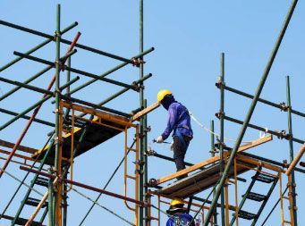 Un trabajador de la construcción está parado encima de un andamio.