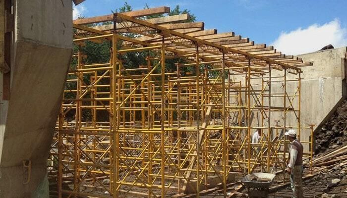 Un sitio de construcción con muchos andamios y un hombre empujando una carretilla