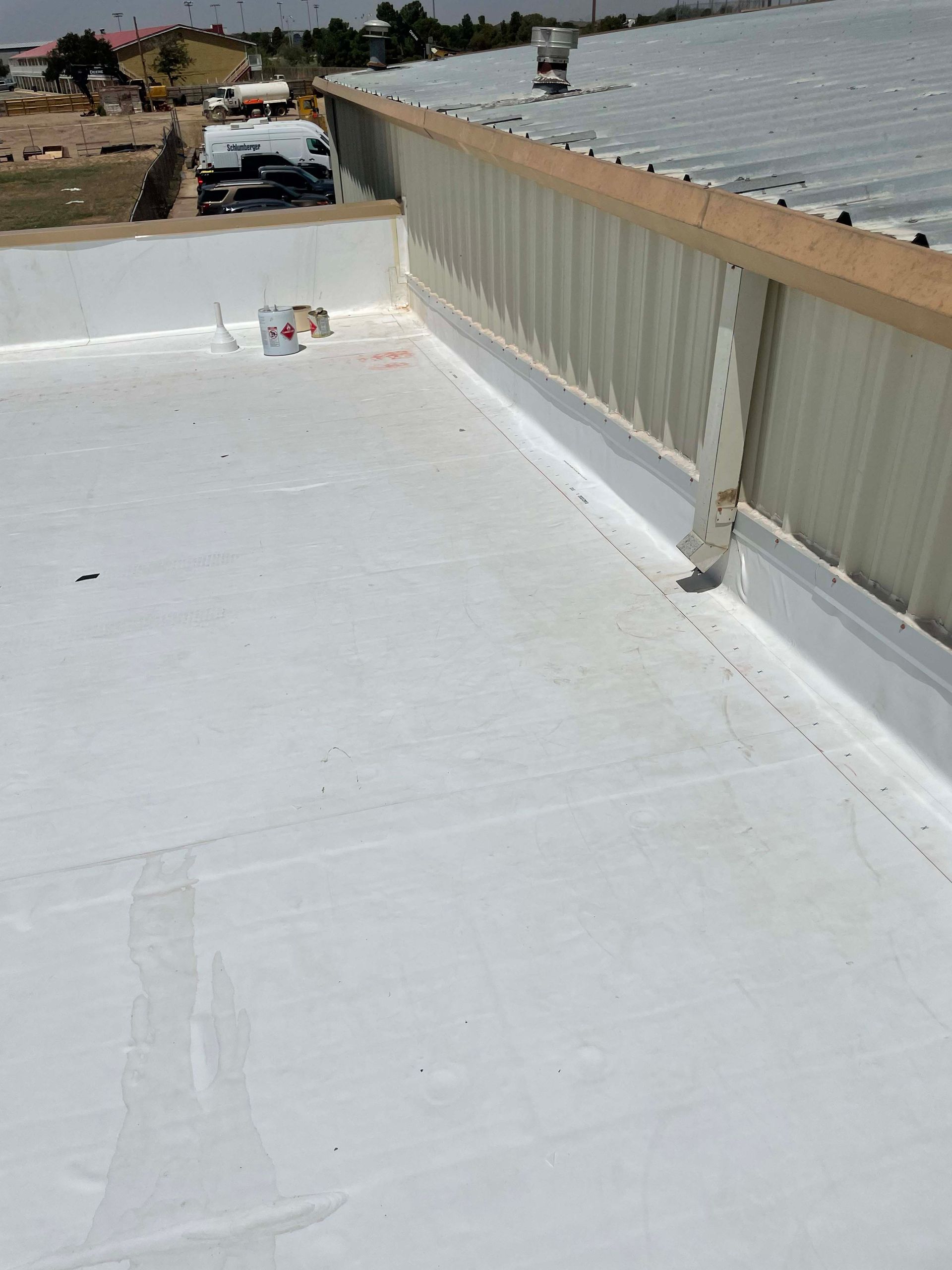 White commercial roof with a metal edge and clear sky.