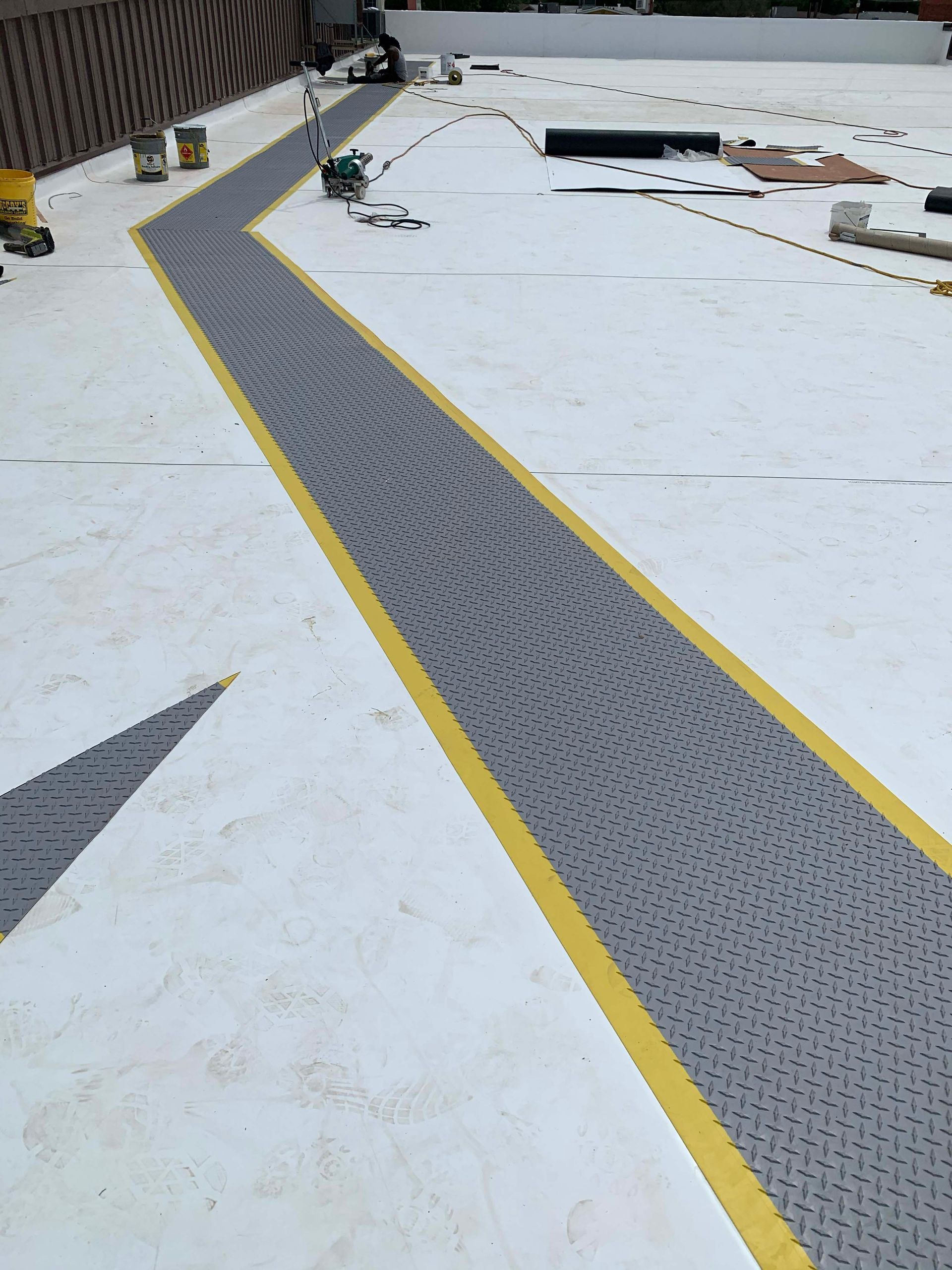 Gray and yellow walkway on a white roof, possibly for roof access.