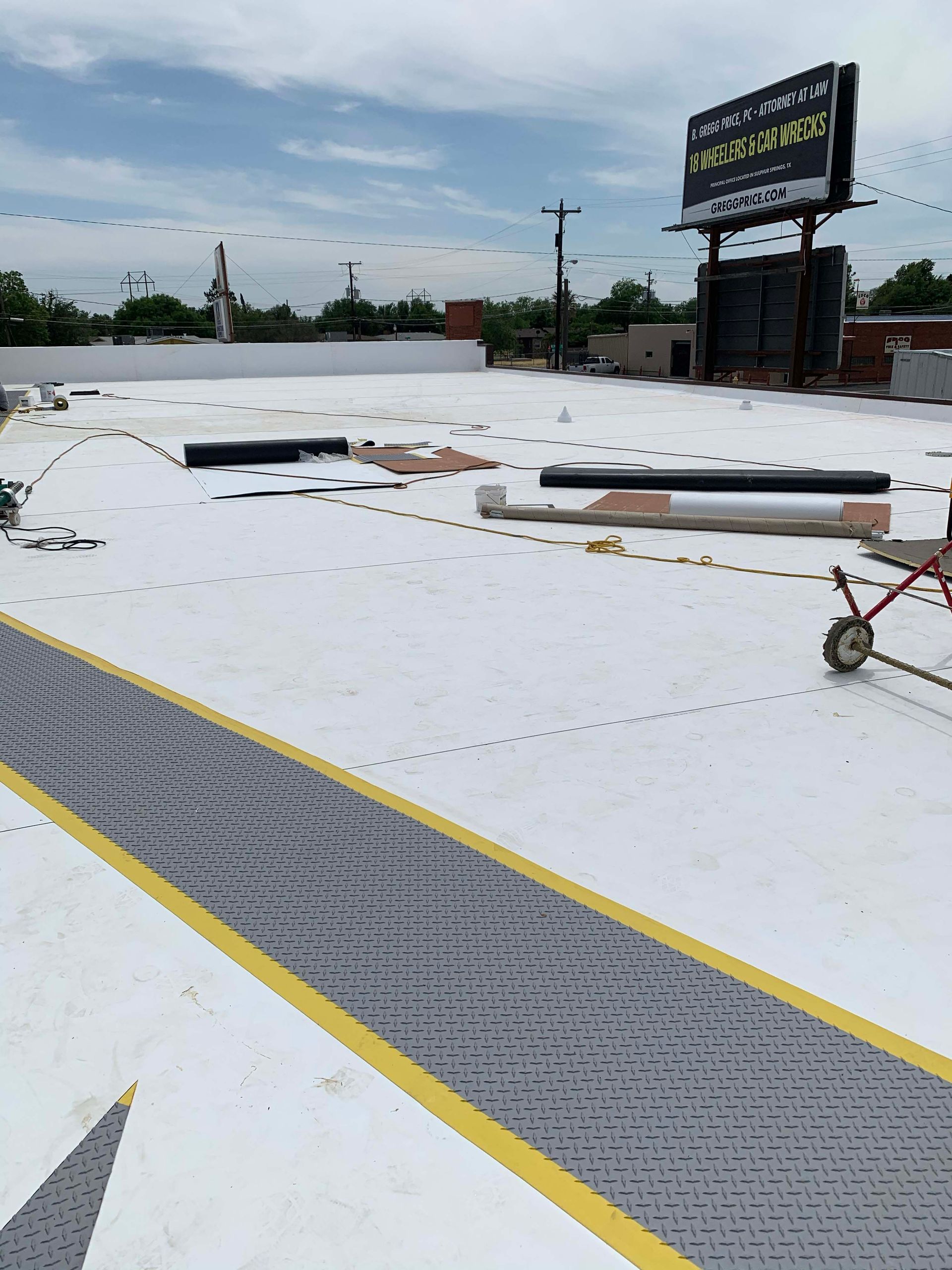 Flat commercial rooftop with white membrane, safety path, and equipment.