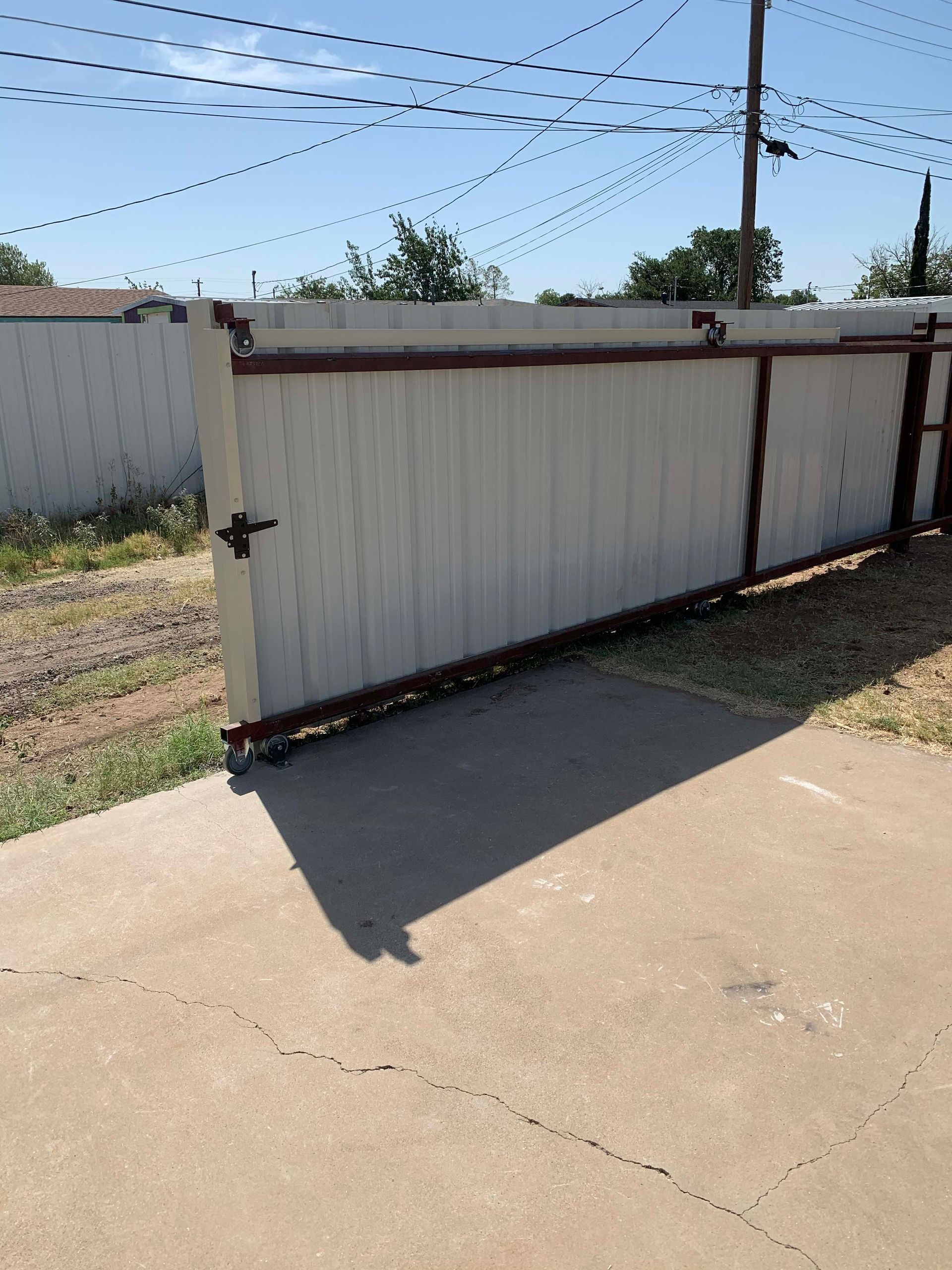 White wooden gate in an outdoor setting, partially open on a concrete surface.