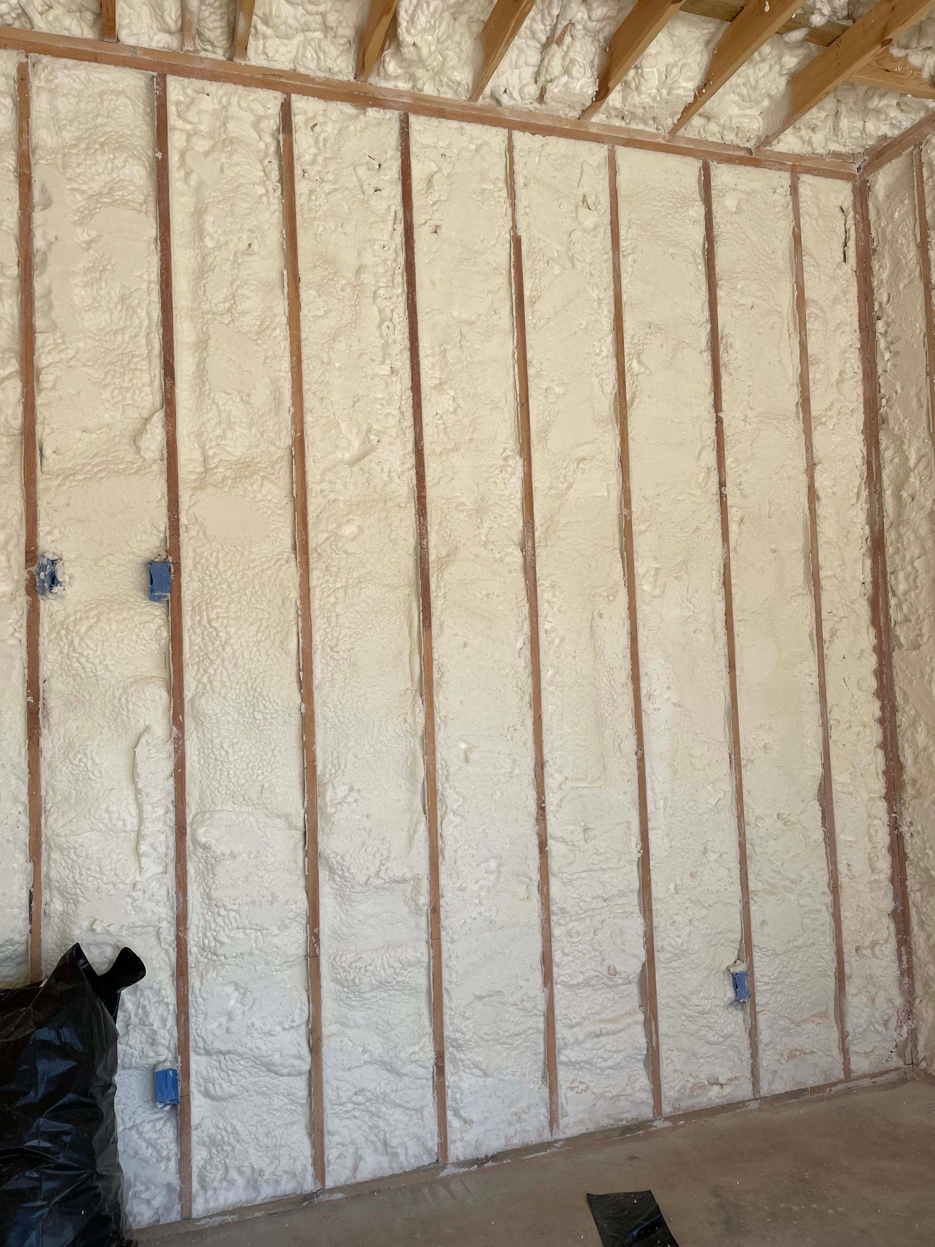 Interior wall with spray foam insulation between wooden studs.
