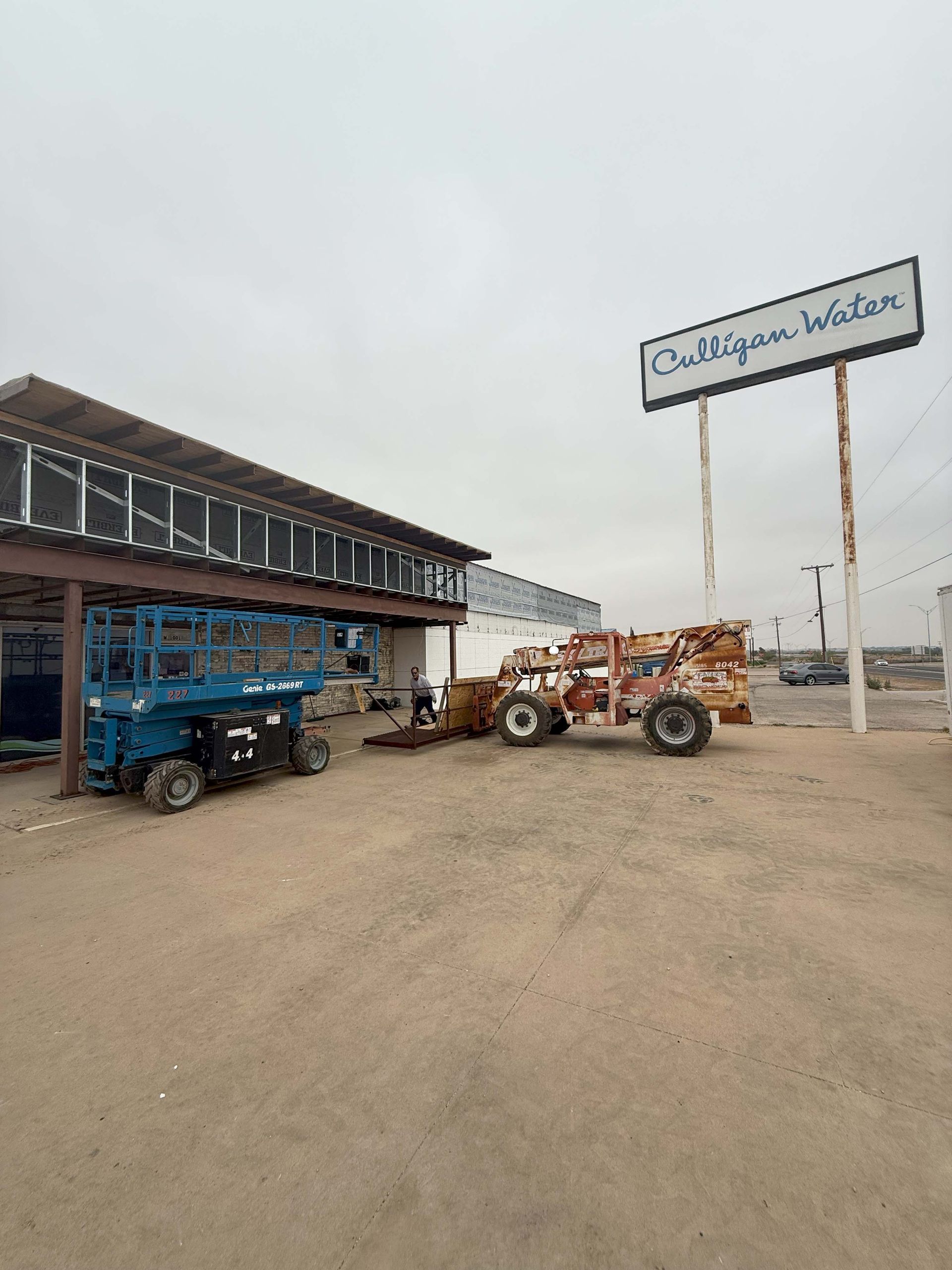 Exterior view of Mulligan Water building with equipment and sign under an overcast sky.