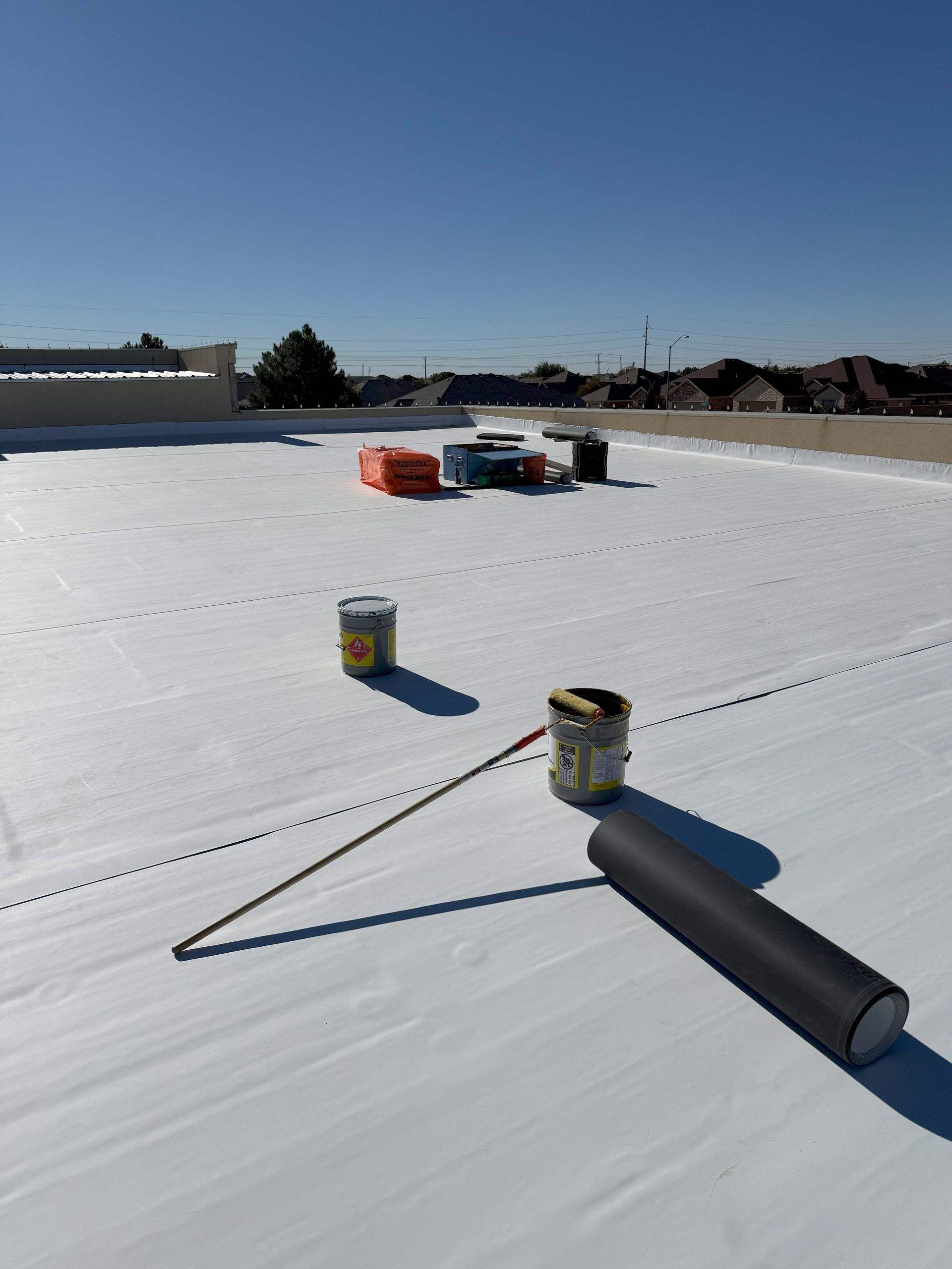 White roof with tools and equipment under a clear blue sky.