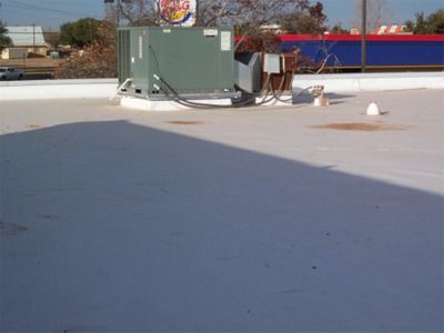 A flat, white commercial roof with HVAC units. Burger King sign in the background.