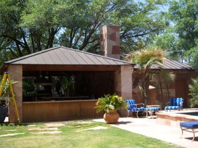 Outdoor bar and seating area with stone walls, brown roof, and blue chairs.