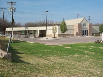 A tan building with a drive-thru lane and parking lot on a sunny day.