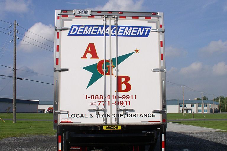 L'arrière d'un camion de déménagement blanc de la société « Déménagement AGB » affiche leur logo, leurs numéros de téléphone et les services proposés.
