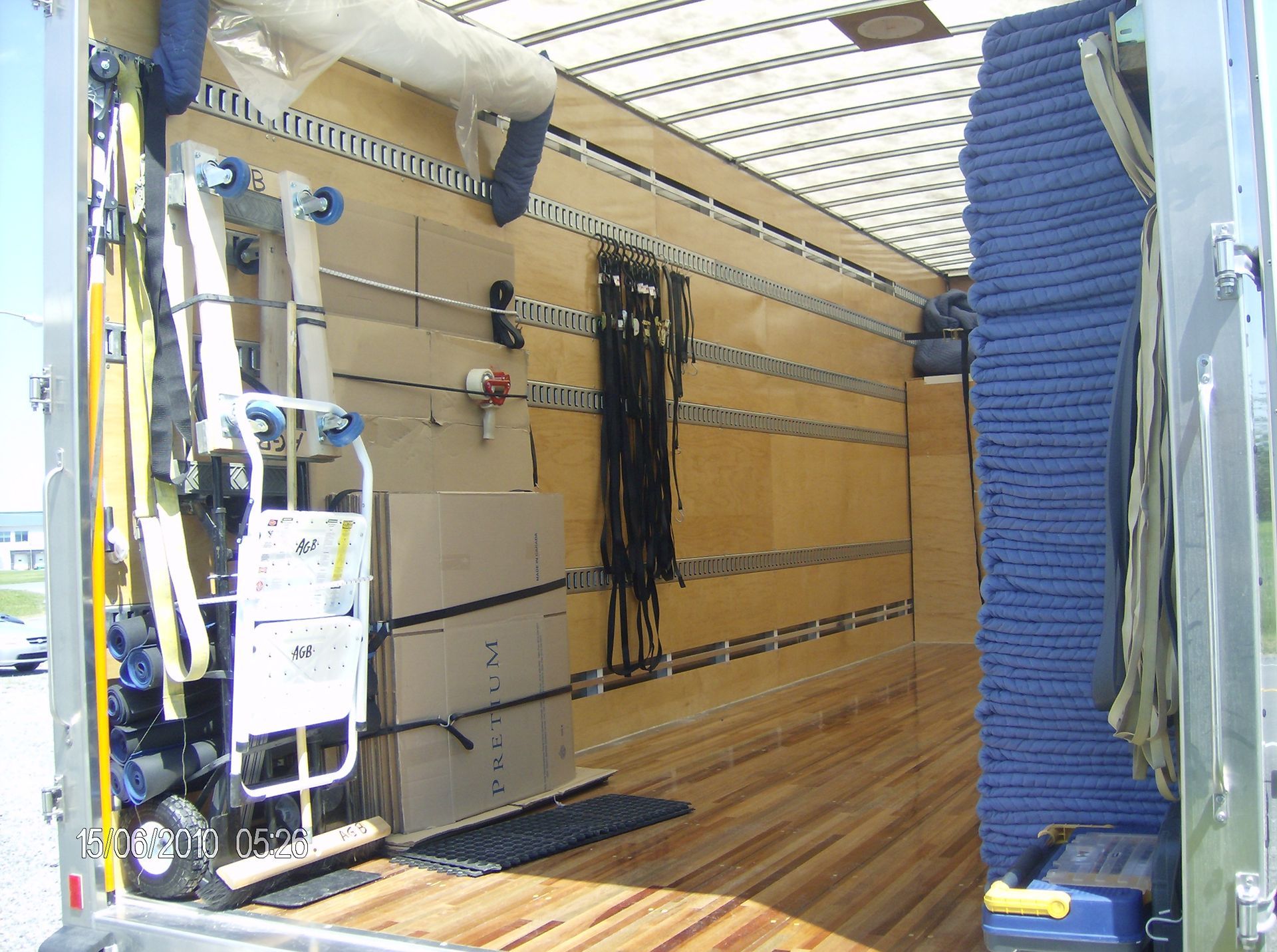 À l'intérieur d'un camion de déménagement : cartons, diable, sangles et rembourrage de protection contre le mur.