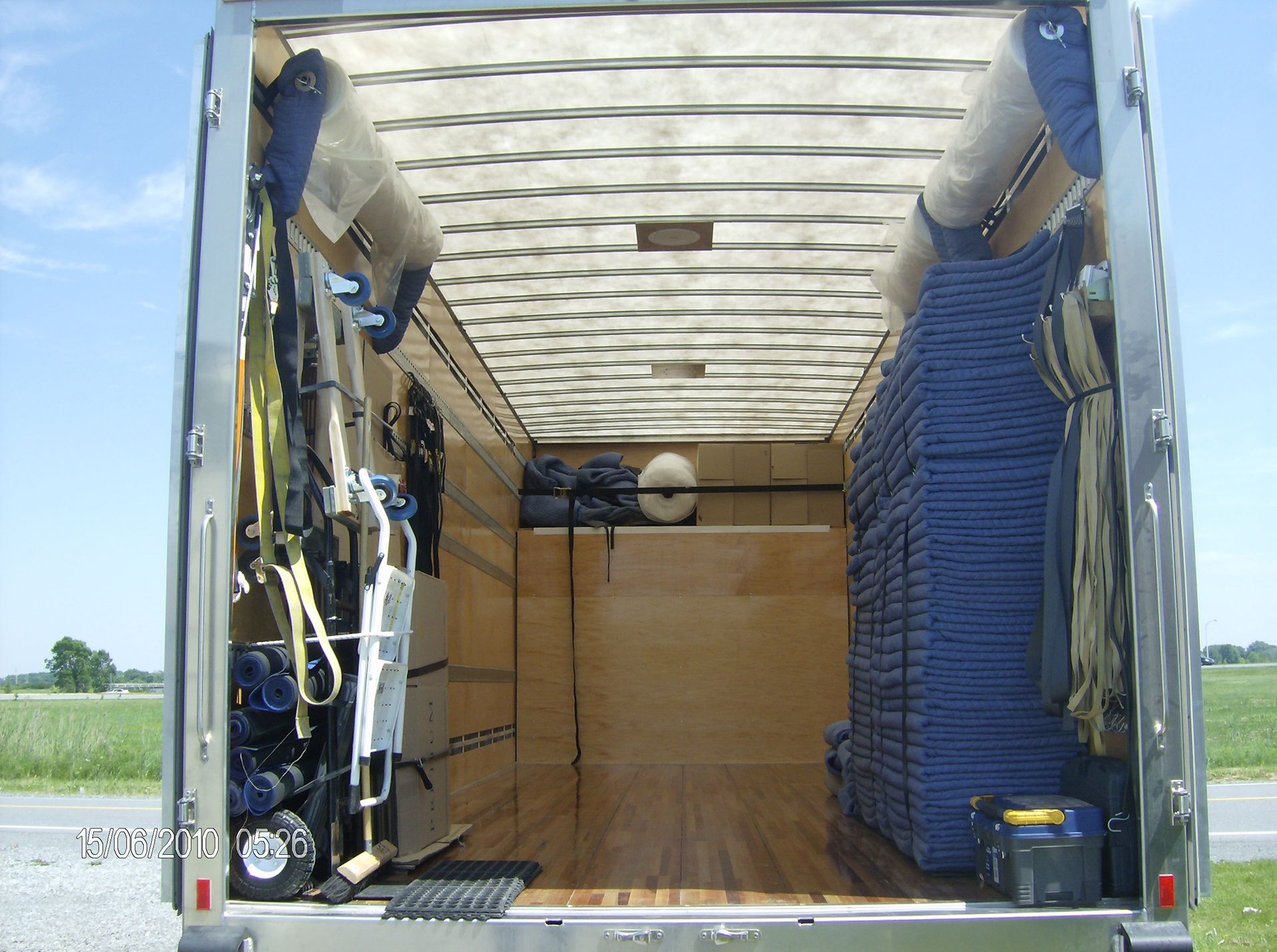 Intérieur d'une remorque, montrant le matériel stocké. Couleurs dominantes : beige et bleu.