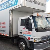 Camion de déménagement, cabine blanche avec logos rouges et bleus, stationné. Inscription « Déménagement » sur le côté.