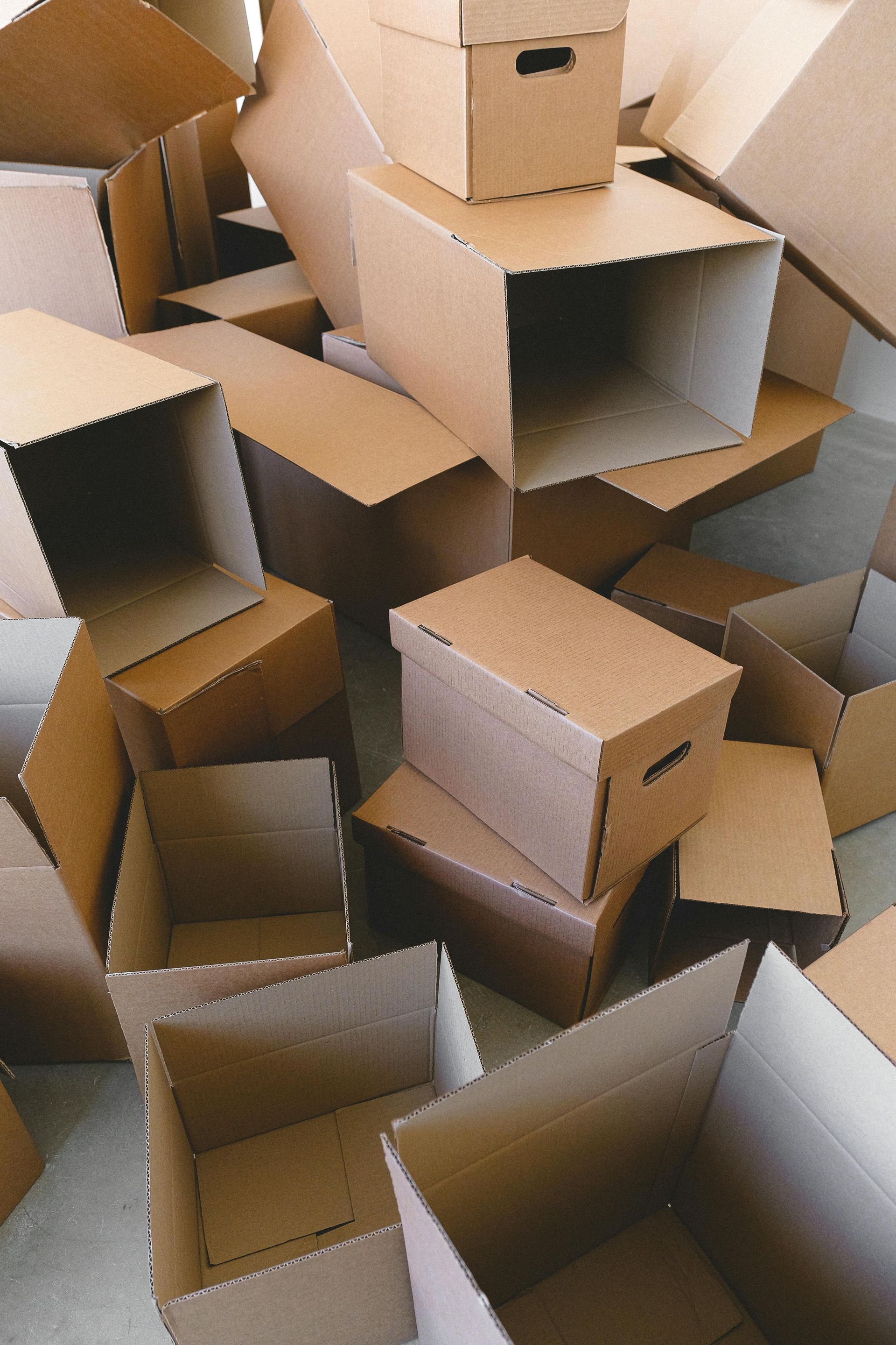 Un tas de cartons de déménagement bruns, ouverts et fermés.