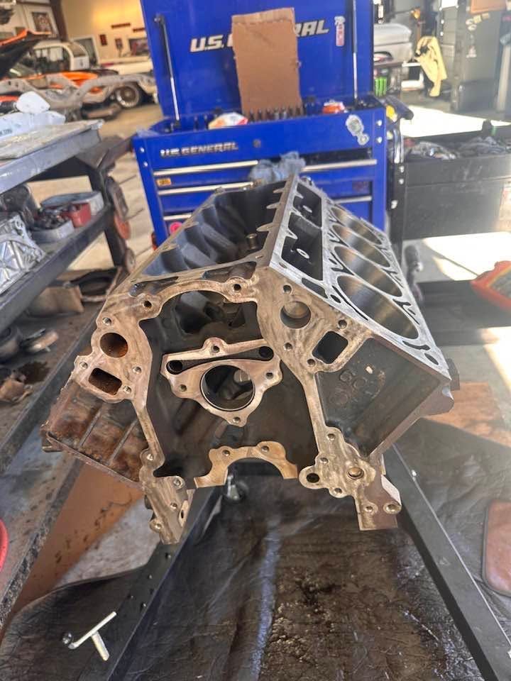 Partially disassembled engine block on a shop floor in front of a blue tool chest and workbench. | Pro Veterans Automotive