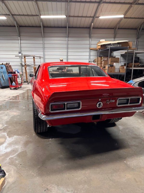Red classic muscle car in a workshop garage, rear view with red paint and chrome trim. | Pro Veterans Automotive